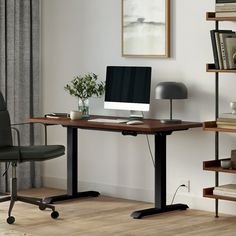 a desk with a computer on top of it in front of a book shelf filled with books