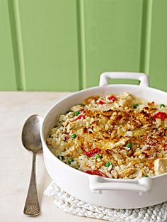 a white casserole dish filled with rice and vegetables on a doily next to a green wall