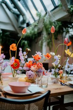 the table is set with flowers in vases, plates and utensils on it