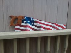 a pair of scissors and an american flag on a wooden rail with wood slats