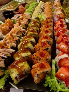 many different types of sushi are lined up on a table with other food items