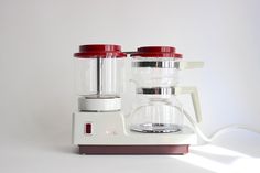 a blender sitting on top of a white counter next to a red and white object