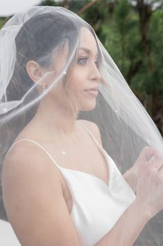 a woman wearing a wedding veil and holding a cell phone in her hand while looking at the camera