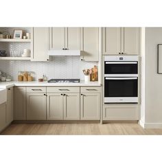 a kitchen with white cabinets and an oven in the center, along with wooden flooring