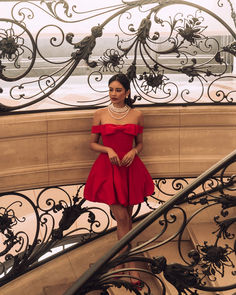 a woman in a red dress is standing on some stairs