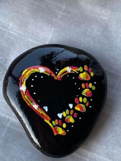 a black heart shaped rock with colorful designs on it