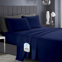 a bed with blue sheets and pillows in a bedroom