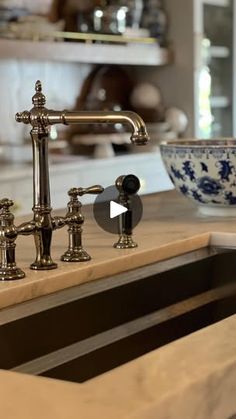 a kitchen sink with two faucets and a bowl on the counter in front of it