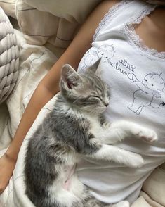 a small kitten laying on top of a woman's stomach