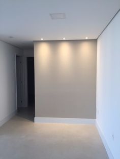 an empty room with white walls and lights on either side of the wall, in front of a doorway