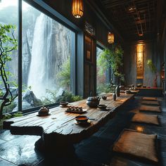 a long table with plates and bowls on it in front of a window overlooking a waterfall