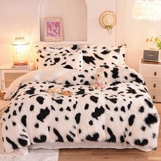 a bed with black and white animal print comforter on it in a bedroom next to a dresser