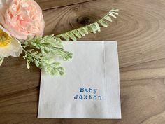 a paper napkin with the word baby jaxon on it next to a flower