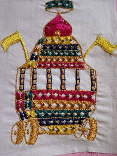 a machine embroidered onto a white piece of cloth with gold trimmings and beads