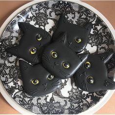 three black cats are sitting on a plate