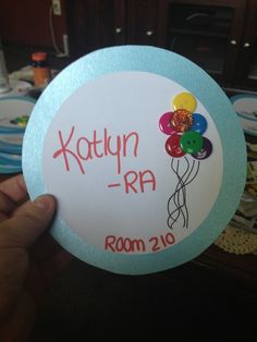 a person holding up a round sticker with balloons and confetti on it