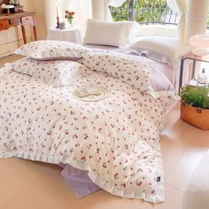 a bed with white sheets and pink flowers on it in front of a large window