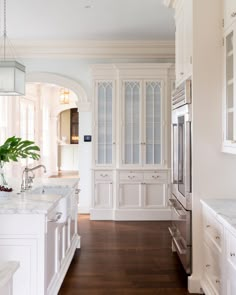 a kitchen with white cabinets and marble counter tops, along with hardwood flooring in the middle