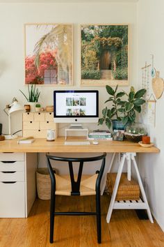 a desk with a computer on top of it next to some plants and other items