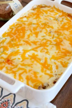 a casserole dish with cheese and meat in it on a table next to bread