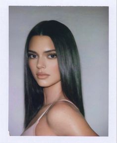 a woman with long black hair is looking at the camera while wearing a tank top