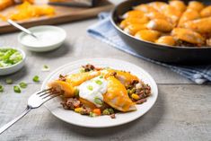 a white plate topped with food next to a skillet filled with cheese and meat