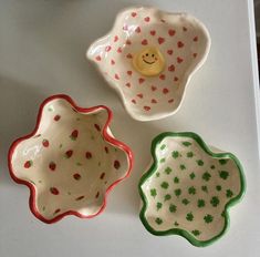 three small bowls with designs on them sitting next to each other, one has a yellow rubber duck in the middle