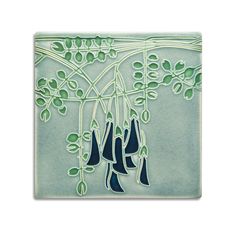 a ceramic tile with blue and green designs on it's sides, hanging from a tree branch