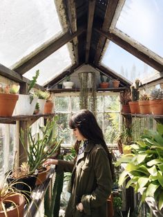 a woman in a greenhouse looking at plants