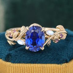 a tan gold ring with a blue stone surrounded by leaves