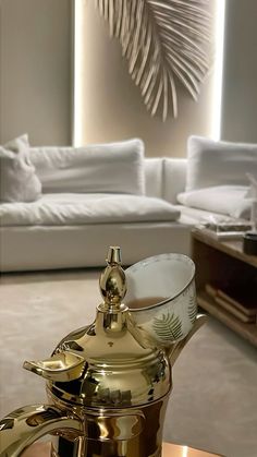 a gold tea pot sitting on top of a glass table next to a white couch