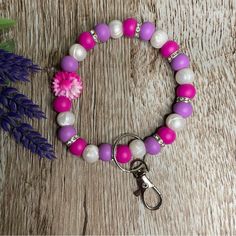 a purple and white beaded bracelet with a pink flower