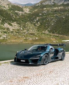 a black sports car parked on the side of a road next to a body of water