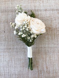 white roses and baby's breath are arranged in a bouquet on a linen background