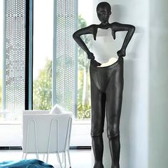 a black mannequin standing next to a white chair