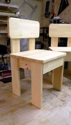 two wooden chairs sitting next to each other on top of a hard wood floor in a garage