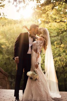 a bride and groom kissing in front of the sun