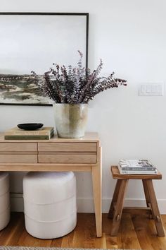 a vase with flowers sitting on top of a wooden table next to two stools