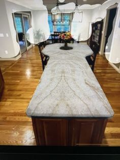 a large kitchen with wooden floors and white counter tops in front of a dining room table