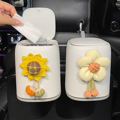 two white vases with flowers on them in a car