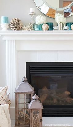 a fireplace with candles and lanterns in front of it on top of a mantel