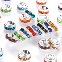 many different colored rings on a white surface with one being surrounded by smaller colorful beads