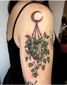 a woman with a tattoo on her arm has a green plant and moon hanging from it