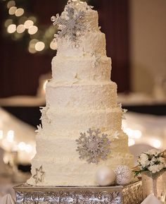 a white wedding cake with silver snowflakes on the top is sitting on a table