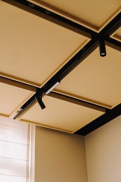 an empty room with white walls and black metal ceiling fans on the ceiling, in front of a window