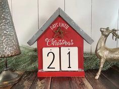 a red house shaped clock sitting on top of a wooden table next to a christmas tree