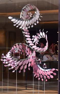 a window display with pink and white decorations in it's glass front windows,