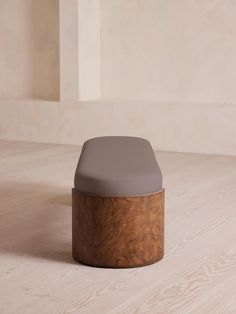 a wooden stool sitting on top of a hard wood floor next to a white wall