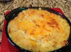 a cheesy casserole is sitting on a red place mat next to a spoon