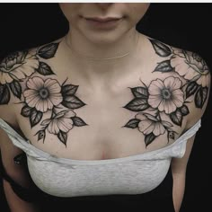 a woman's chest with flowers and leaves tattooed on her upper half - arm